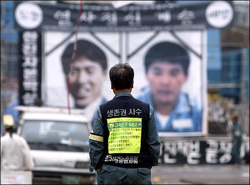 2003년 12월 부산 한진중에서 한 노동자가 김주익 곽재규씨의 대형 영정을 바라보며 걸어가고 있다.